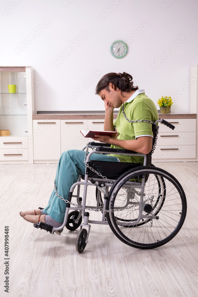 Young male invalid in wheel-chair suffering at home Young male invalid in wheel-chair suffering at home
