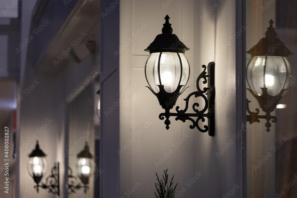 wrought-iron wall lamp of outdoor building at night time. wrought-iron wall lamp of outdoor building at night time.