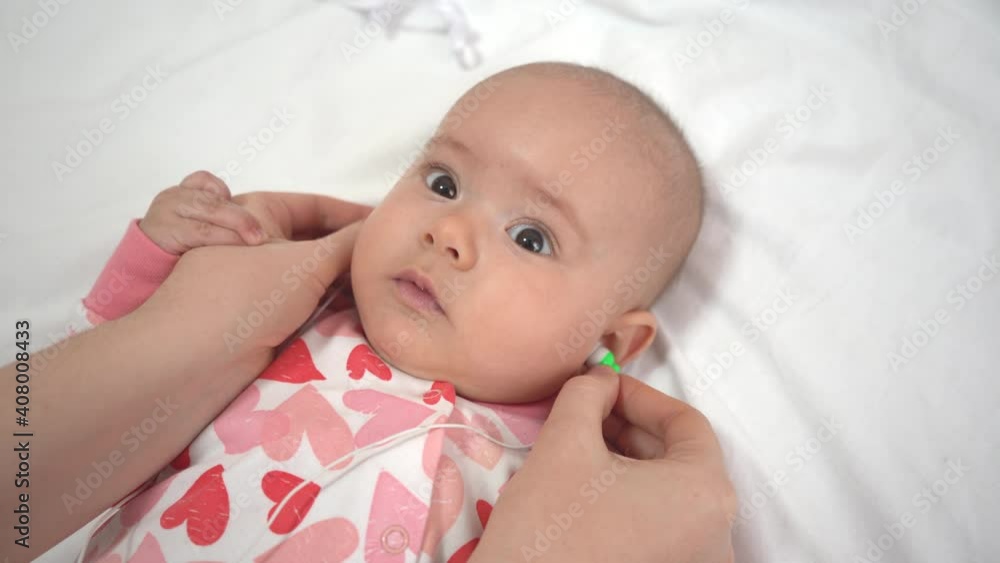 Mom gives her newborn daughter headphones with playing music