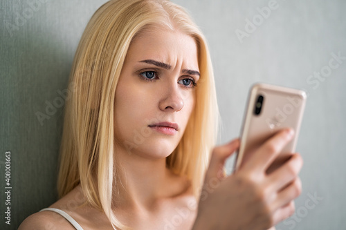 The girl looks at the phone frowning eyebrows