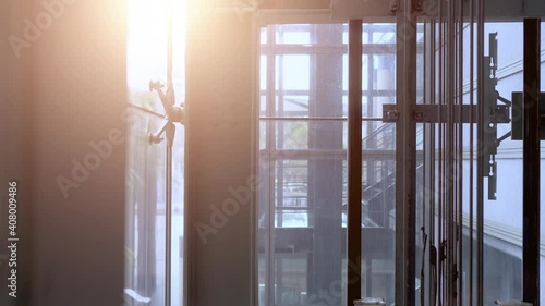 Moving elevator in modern commercial building. The elevator goes up. There is a flash of sunlight in the upper left corner. The mechanical structure inside the elevator.