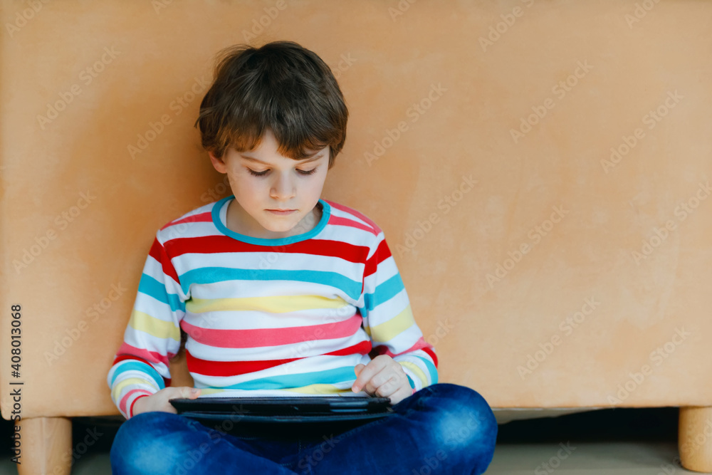 Little school kid boy making homework with tablet. Schoolchild reading and learning with computer, searching for information in internet. Little school kid boy making homework with tablet. Schoolchild reading and learning with computer, searching for information in internet.