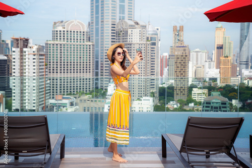 Photography Asian lady enjoy selfie in swimming pool in rooftop of hotel