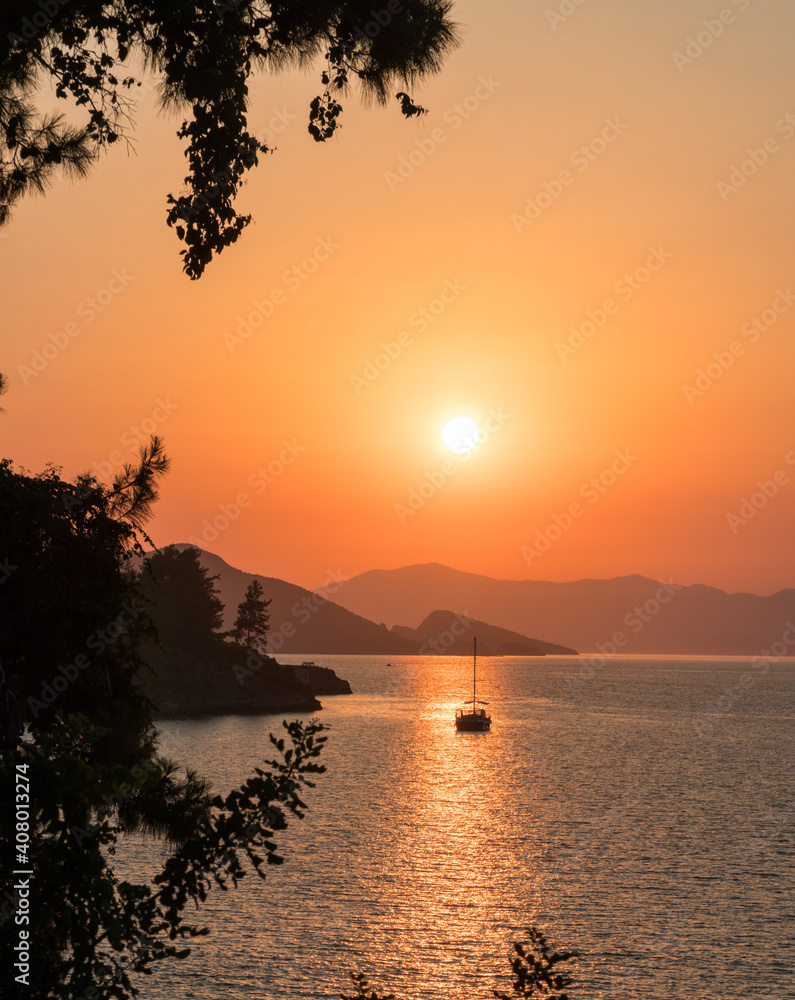 Calm sea and sunset. Sun is setting behind the hills on the horizont.  Beautiful nature background.