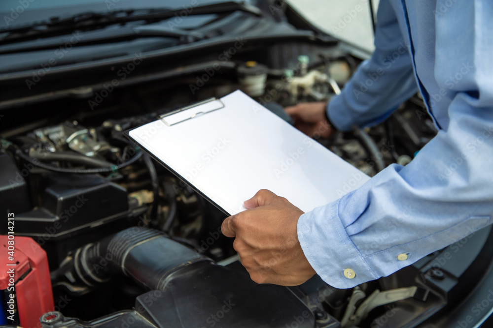 Auto mechanic using checklist for car engine systems after fixed. Concepts of car fix and checking repair and service maintenance.