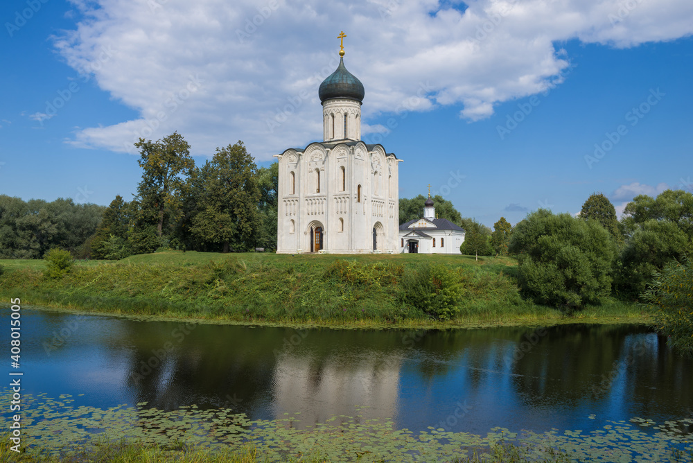 View of the Church of the Intercession on the Nerl and the Church of the Three Saints of the Ecumenical on a sunny summer day. Bogolyubovo. Vladimir region, Russia