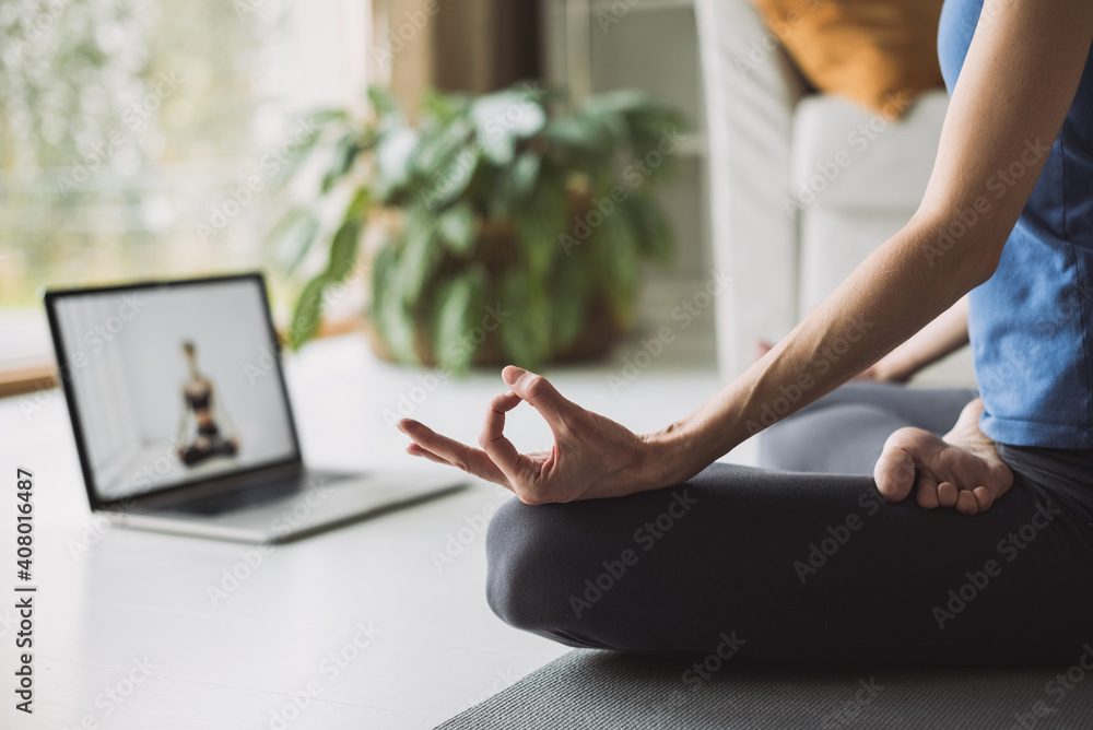 Fototapeta Young woman practicing yoga at home, online video training, Girl doing exercises and meditate, Yoga, balance, meditation, relaxation, healthy lifestyle, online training class concept