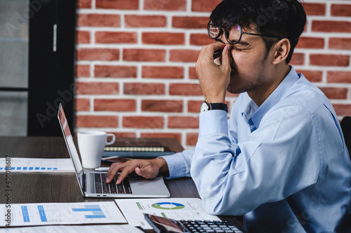 Photography asian businessman get stress and headache when working with laptop on desk at modern office