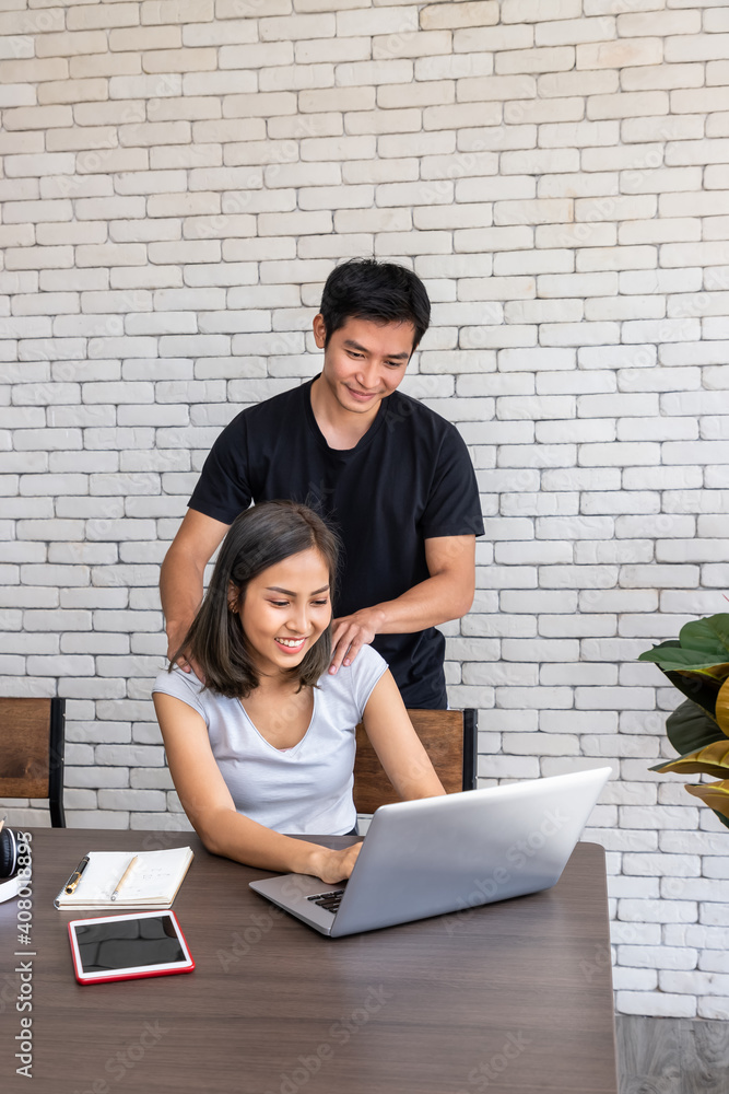 Asian man husband motivate support wife woman freelancer working at home, sitting at desk dining table in living room Asian man husband motivate support wife woman freelancer working at home, sitting at desk dining table in living room