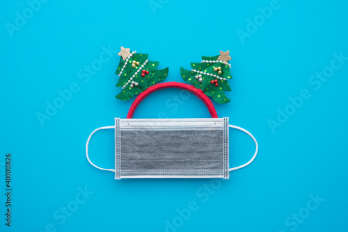 Covid-19 in Christmas festival celebration concept. Flat lay of festive Christmas xmas made from decorative object and protective face mask on blue background with copy space.