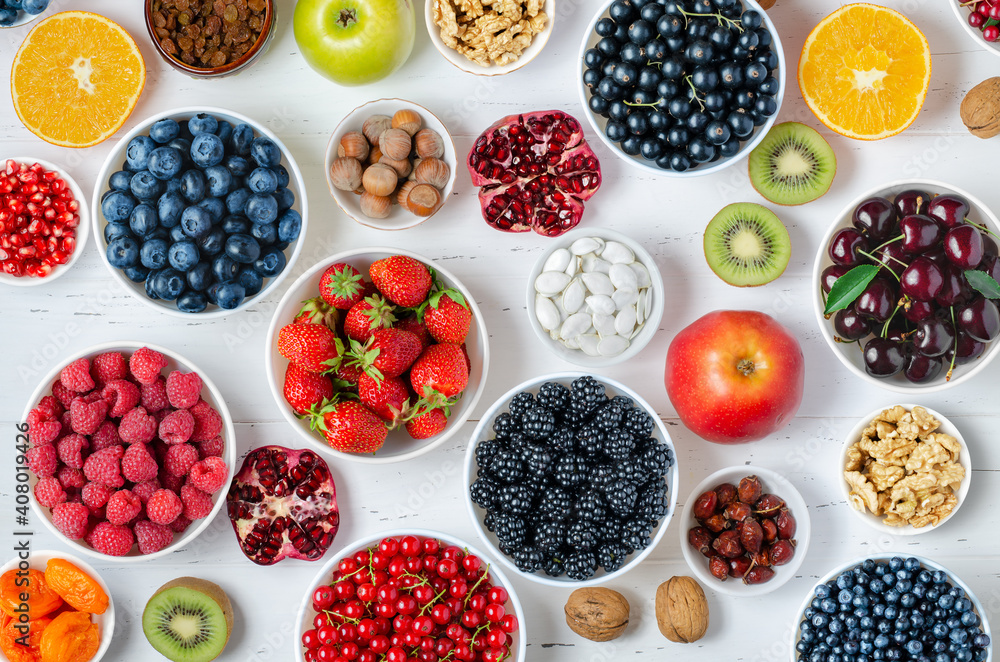 Fresh berries, fruits, nuts on a white wooden background. The concept of healthy eating. Food contains vitamins and trace elements Fresh berries, fruits, nuts on a white wooden background. The concept of healthy eating. Food contains vitamins and trace elements