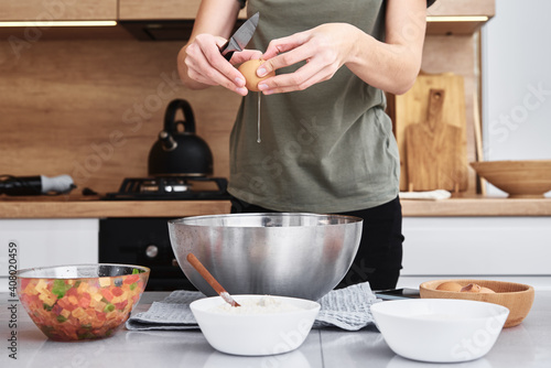 Fototapeta Naklejka Na Ścianę i Meble -  Woman in kitchen cooking a dough. Hands breaks an egg into a bowl