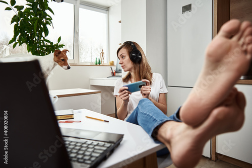 Woman listening online course in headphones, distance education. Freelancer sitting at workplace and procrastinating. Lazy and distracted employee at remote work photo