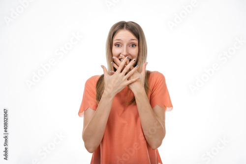 Worried blond girlcover opened mouth palms and looking with surprised expression. Studio shot  white background