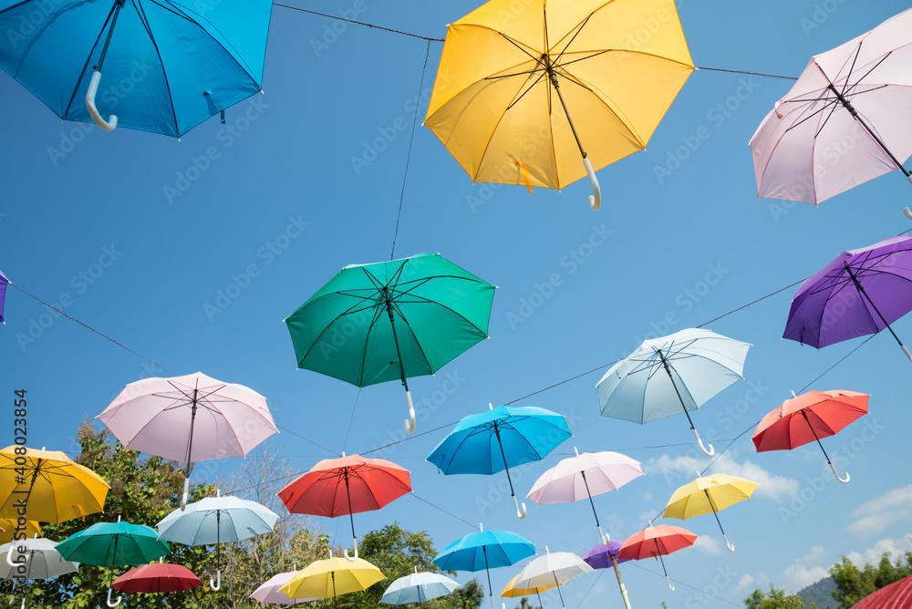 Colorful umbrella decoration in day market festival in city park with blue sky background. Outdoor summer festival concept.