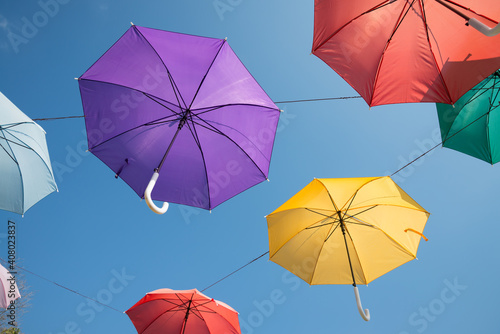 Colorful umbrella decoration in day market festival in city park with blue sky background. Outdoor summer festival concept.
