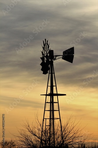 windmill at sunset with a colorful sky and clouds out in the country north of Hutchinson Kansas USA.