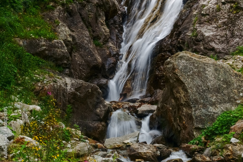 waterfall between rocks with flowers and plants on the side