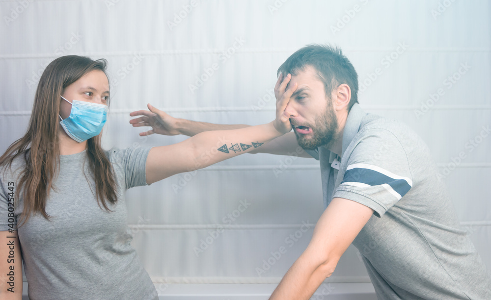 A young woman in a medical mask holds her hand in front of her and holds man at a distance. The concept of social distance and warning not to get closer in the face of the coronavirus pandemic. A young woman in a medical mask holds her hand in front of her and holds man at a distance. The concept of social distance and warning not to get closer in the face of the coronavirus pandemic.