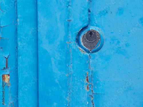 Blue metal old keyhole on a worn out metal sheet garage door