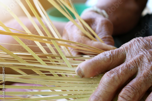 Old man's hands are weaving bamboo, Isan culture, Thailand. Independent career concept of old age. Thai handmade product. photo