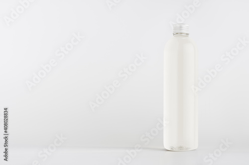 Transparent plastic tall thin bottle with water or cosmetic product, silver cap mockup on white background. Template for design. © finepoints