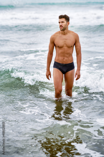 Handsome muscular man bathing on the beach