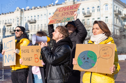 A group of people with banners and a megaphone in hand are protesting in the city square for svae planet clean world act now photo