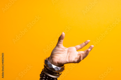 Hand gestures. Women's hand with lots of bracelets, youth fun style. bright yellow background