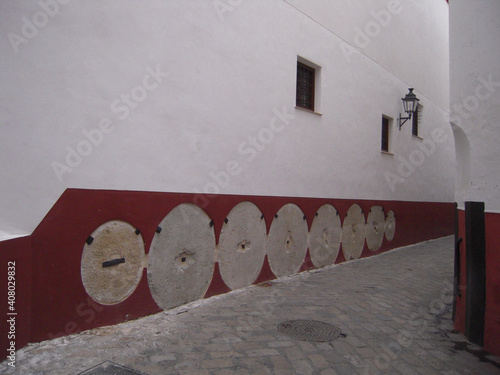 White building with windows, a lamp, and round-shaped holes on a red surfac photo