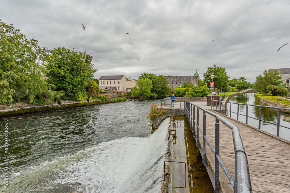 Pedestrian walkway between the River Corrib and a side canal parallel to the river, water entering the river through a small waterfall, Galway Waterways, Galway, Connacht Province, Ireland