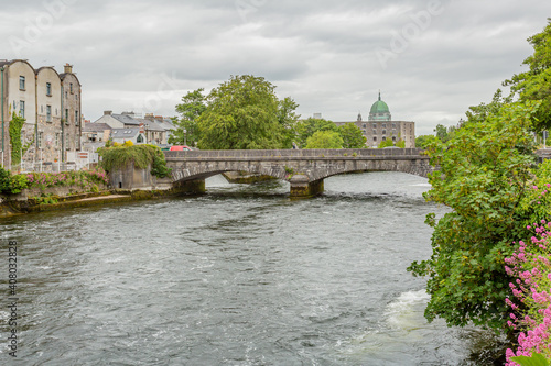 River Corrib with its flowing waters, the William O'Brien bridge and the green dome of the cathedral in the background, Waterways of Galway, cloudy day in Galway, Connacht province, Ireland