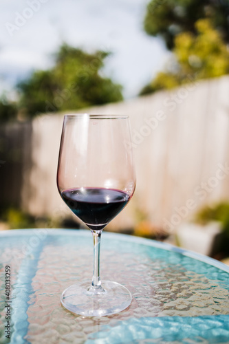 glass of red wine on top of cafe table in al fresco garden