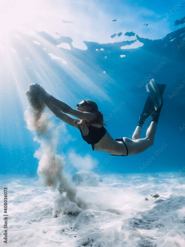 Freediver with fins and white sand in hands over sandy sea. Freediving underwater in ocean