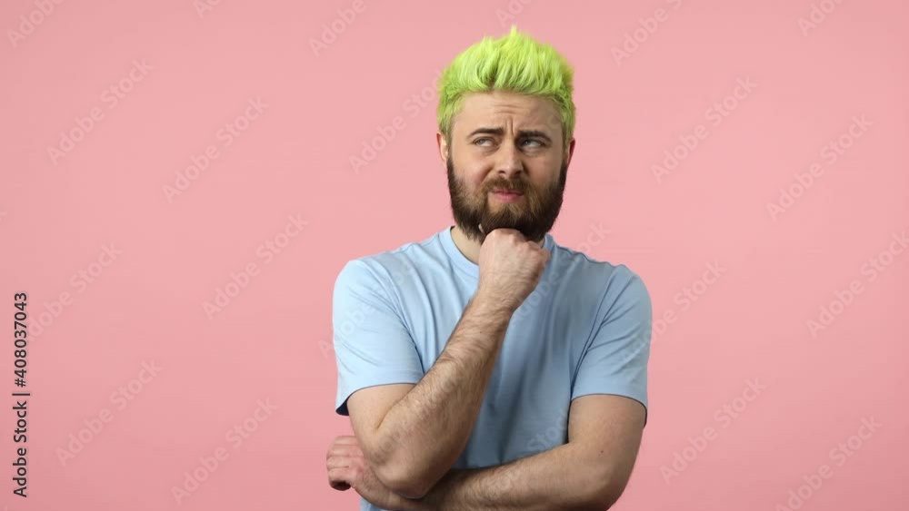 Upset thoughtful man rubbing his bearded chin, planning right strategy, making hard choice and eventually finding solution. Indoor studio shot isolated on pink background Upset thoughtful man rubbing his bearded chin, planning right strategy, making hard choice and eventually finding solution. Indoor studio shot isolated on pink background