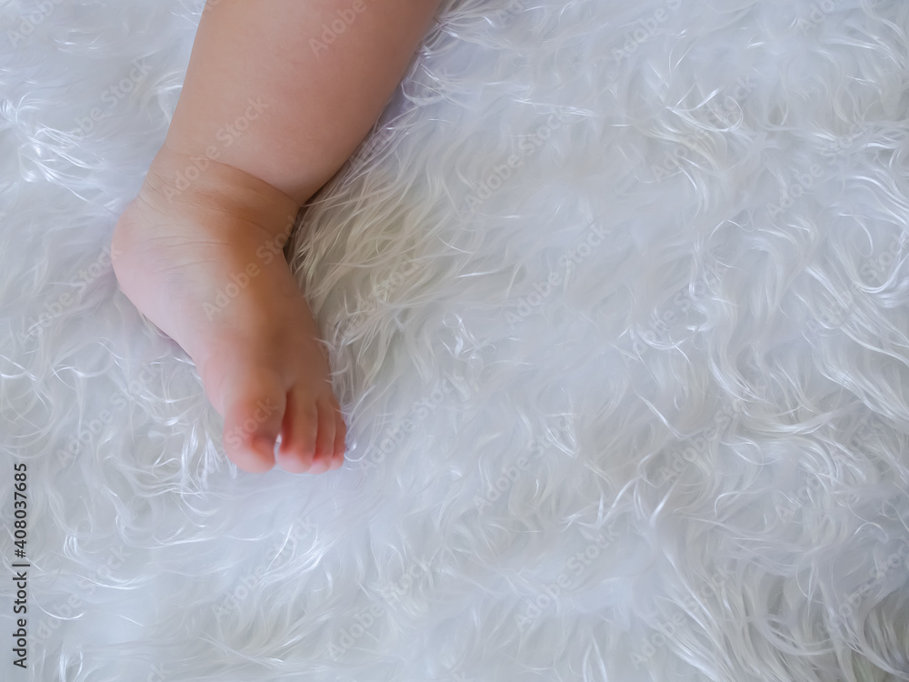 leg littel 1 year old on white fur. flat lay with copy space. child cute concept. leg littel 1 year old on white fur. flat lay with copy space. child cute concept.