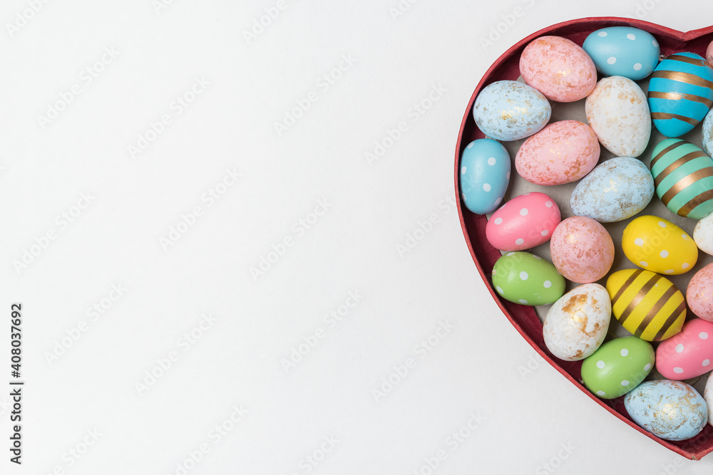 Obraz premium Heart shaped box with Easter eggs on white background. Top view, copy space. Happy easter.