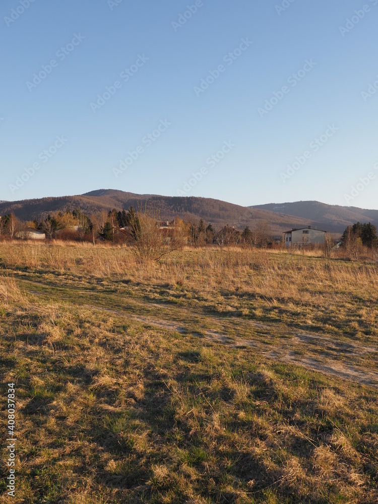 Calm Silesian Beskid Mountains range seen from sport airfield in european Bielsko-Biala city in Poland, clear blue sky in 2020 warm sunny spring day on April at sun set - vertical.