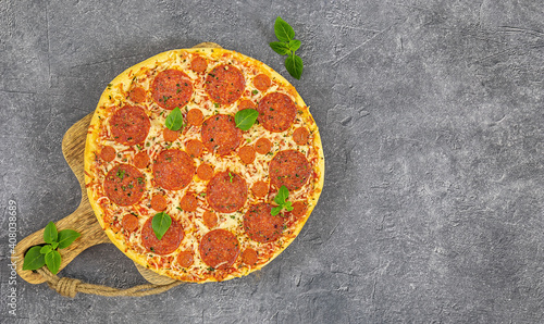 Tasty pepperoni pizza and fresh basil on grey background.