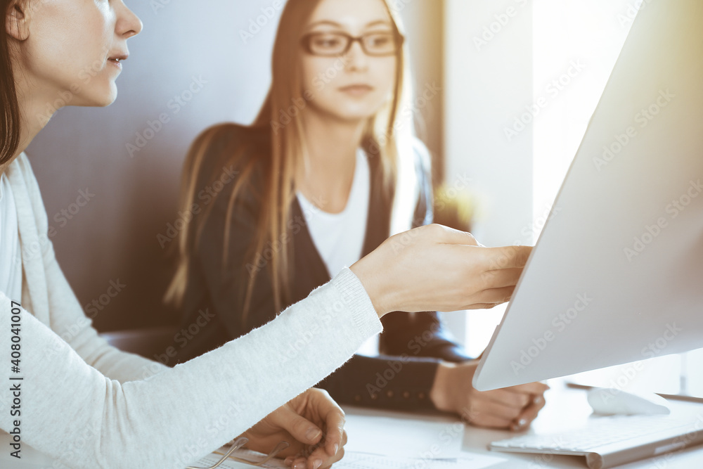 Businesswoman pointing at tablet computer screen while giving presentation to her female colleague. Group of business people working at the desk in office. Teamwork concept Businesswoman pointing at tablet computer screen while giving presentation to her female colleague. Group of business people working at the desk in office. Teamwork concept