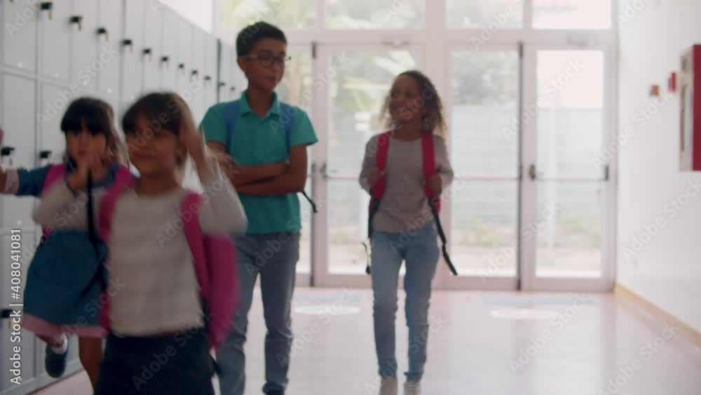 Diverse group of schoolkids of different ages walking in school hallway, talking and hopping. Dolly sot. Education or back to school concept Diverse group of schoolkids of different ages walking in school hallway, talking and hopping. Dolly sot. Education or back to school concept