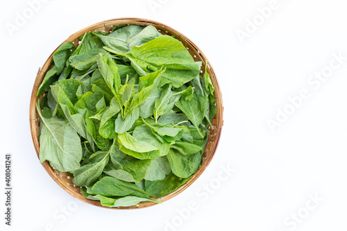 Green spinach in bamboo basket on white background.