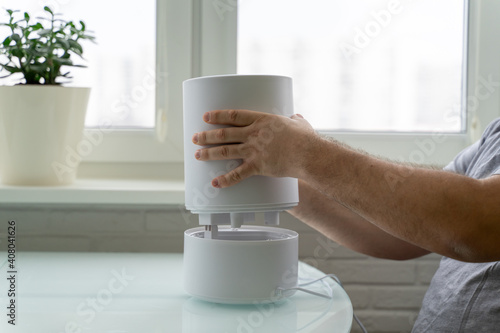 Foto using a humidifier at home. a man disassembles a cleaning device
