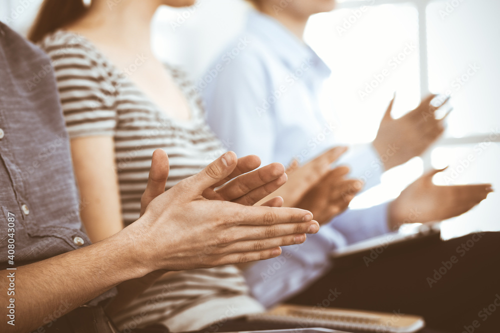Obraz premium Business people clapping at meeting or conference, close-up of hands. Group of unknown businessmen and women in modern white office. Success teamwork, corporate coaching and applause concept