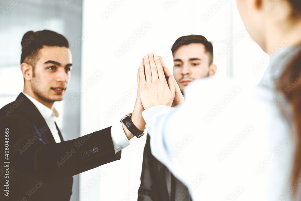 Business people group showing teamwork, joining hands and giving five to each other in modern office. Success concept Business people group showing teamwork, joining hands and giving five to each other in modern office. Success concept