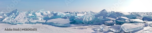 A panorama of the edge of a hummock field with beautiful huge blocks of transparent blue ice on the frozen Lake Baikal on a sunny frosty day. Cool natural background. Unusual winter landscape