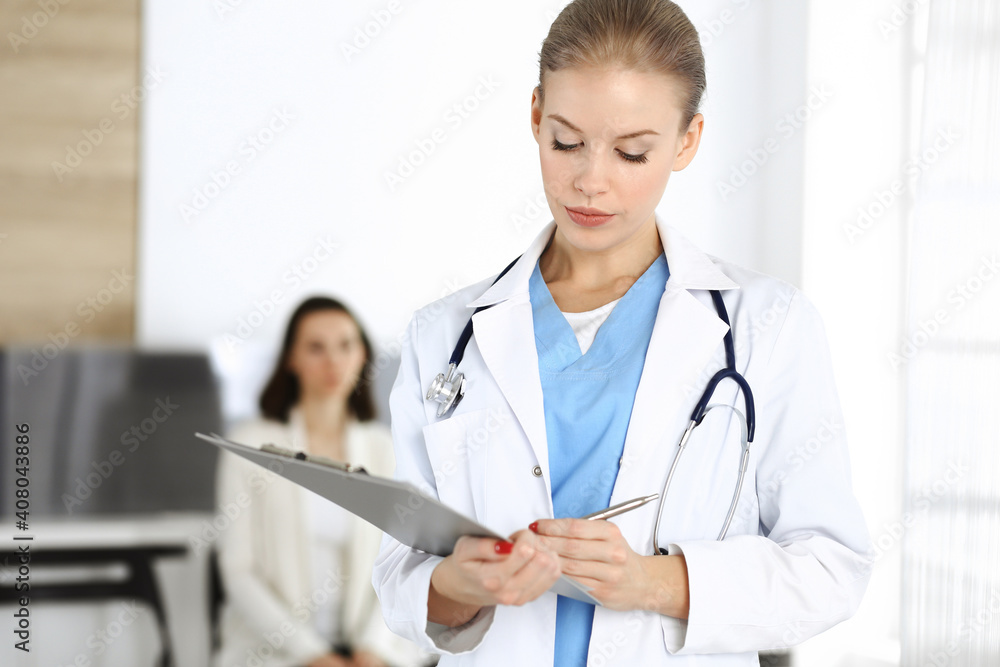 Woman - doctor is using clipboard for filling up medication history record form in clinic at the background of patient. Medicine concept Woman - doctor is using clipboard for filling up medication history record form in clinic at the background of patient. Medicine concept