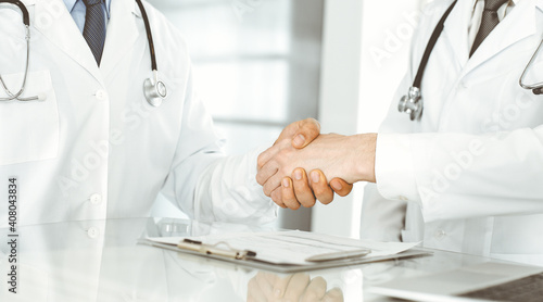 Two doctors are shaking hands as agreement about patient's treatment, close-up. Medical help, medicine concept © Iryna