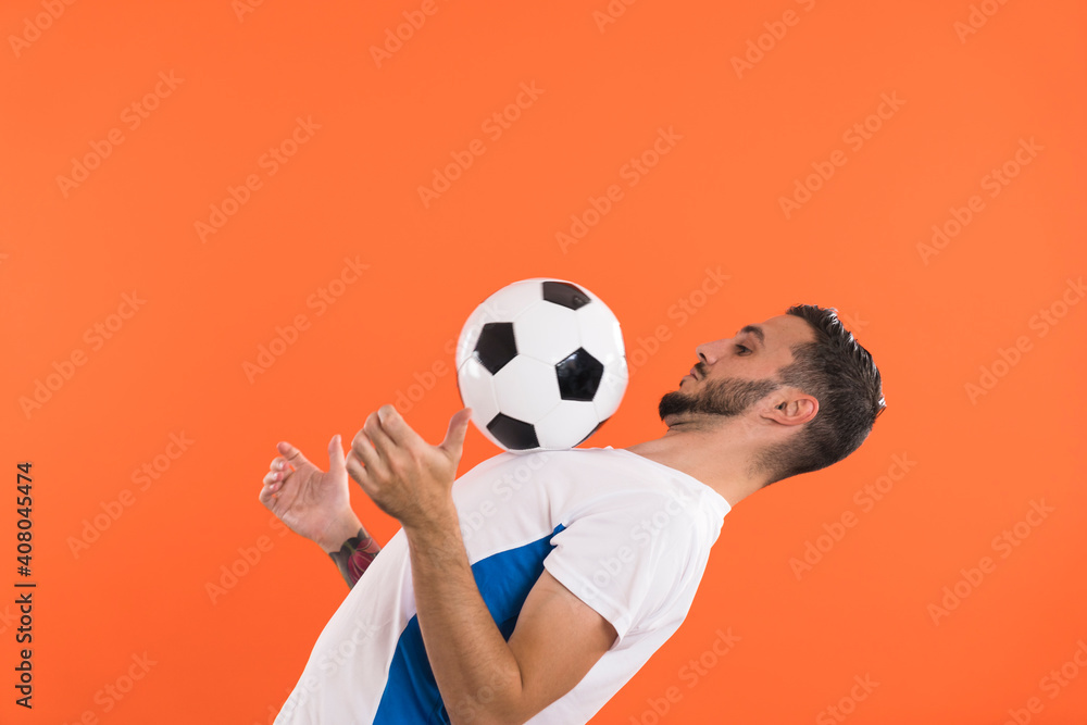 Professional Football player playing with ball isolated on orange background Professional Football player playing with ball isolated on orange background