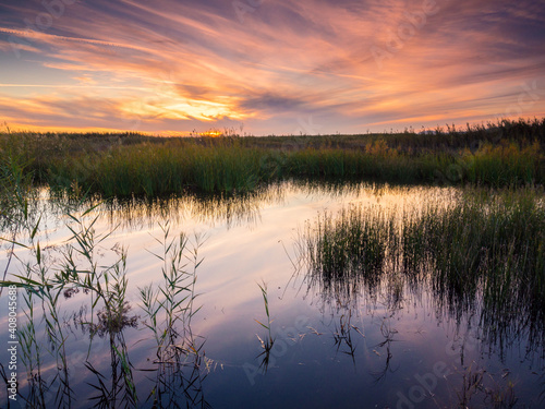 Fototapeta Naklejka Na Ścianę i Meble -  Atardecer en laguna con nubes de color dorado y reflejo en el agua
